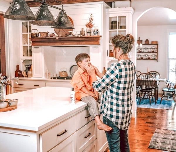 Mother Moisturizes Young Boy on Counter Top With Lotion